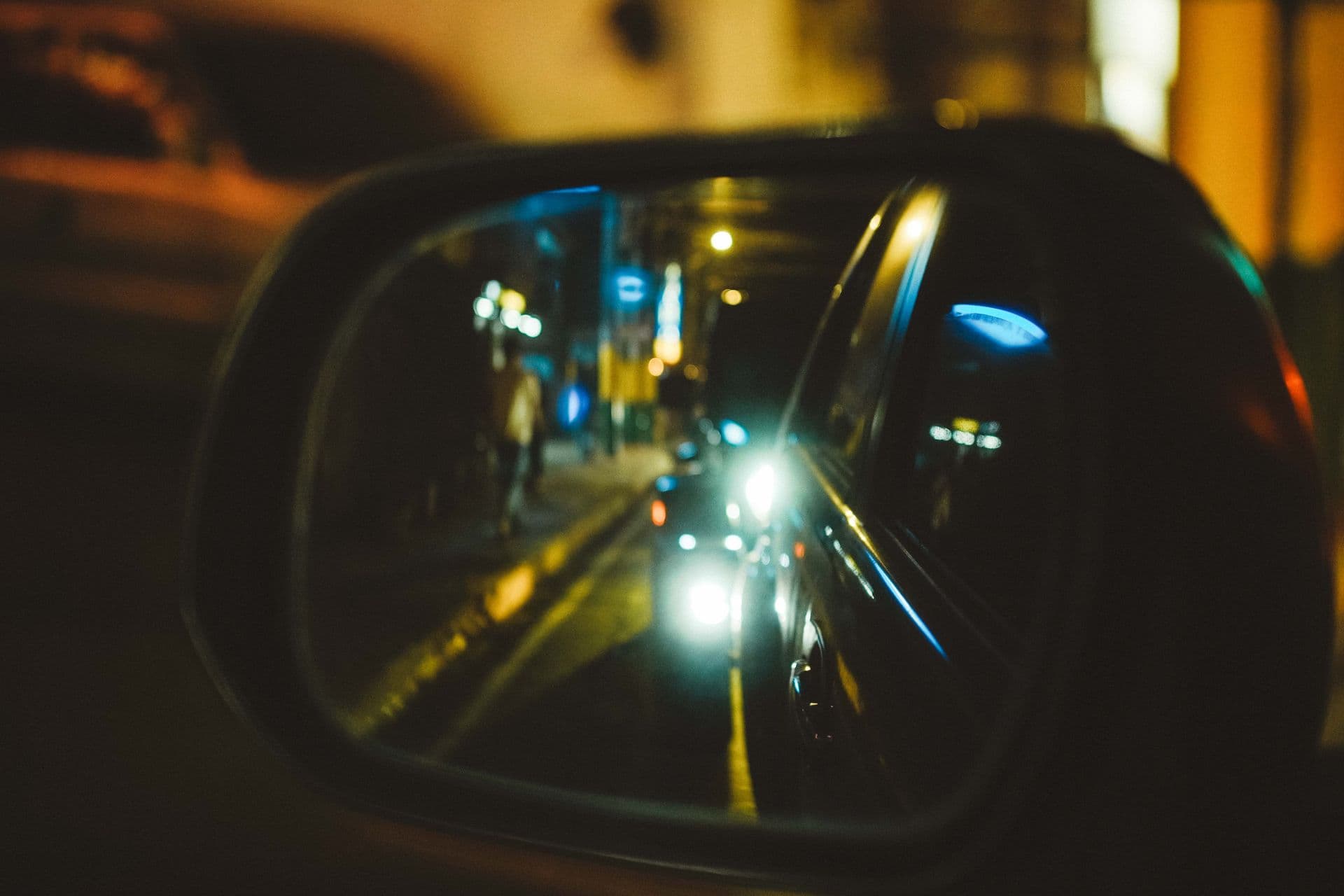 Night street reflected in a car side mirror